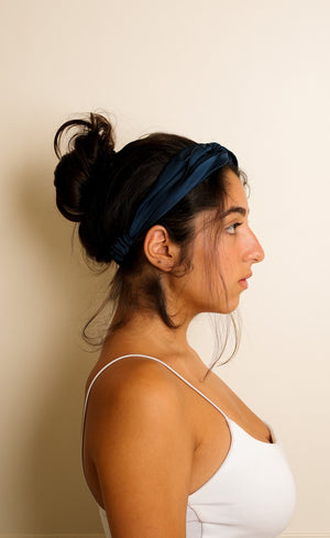 Woman wearing a navy headband against a beige background