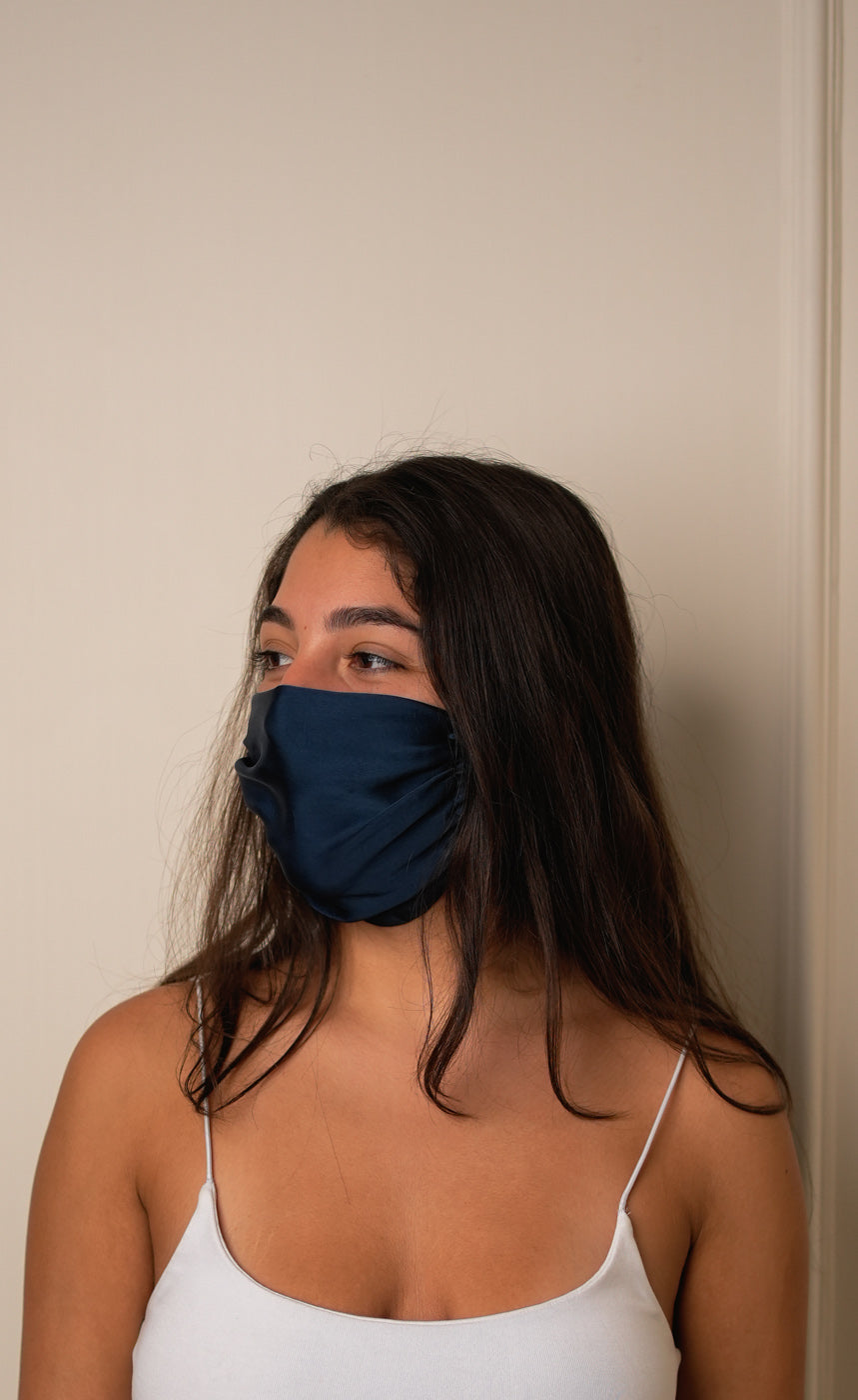 Woman wearing a blue face mask against a plain background