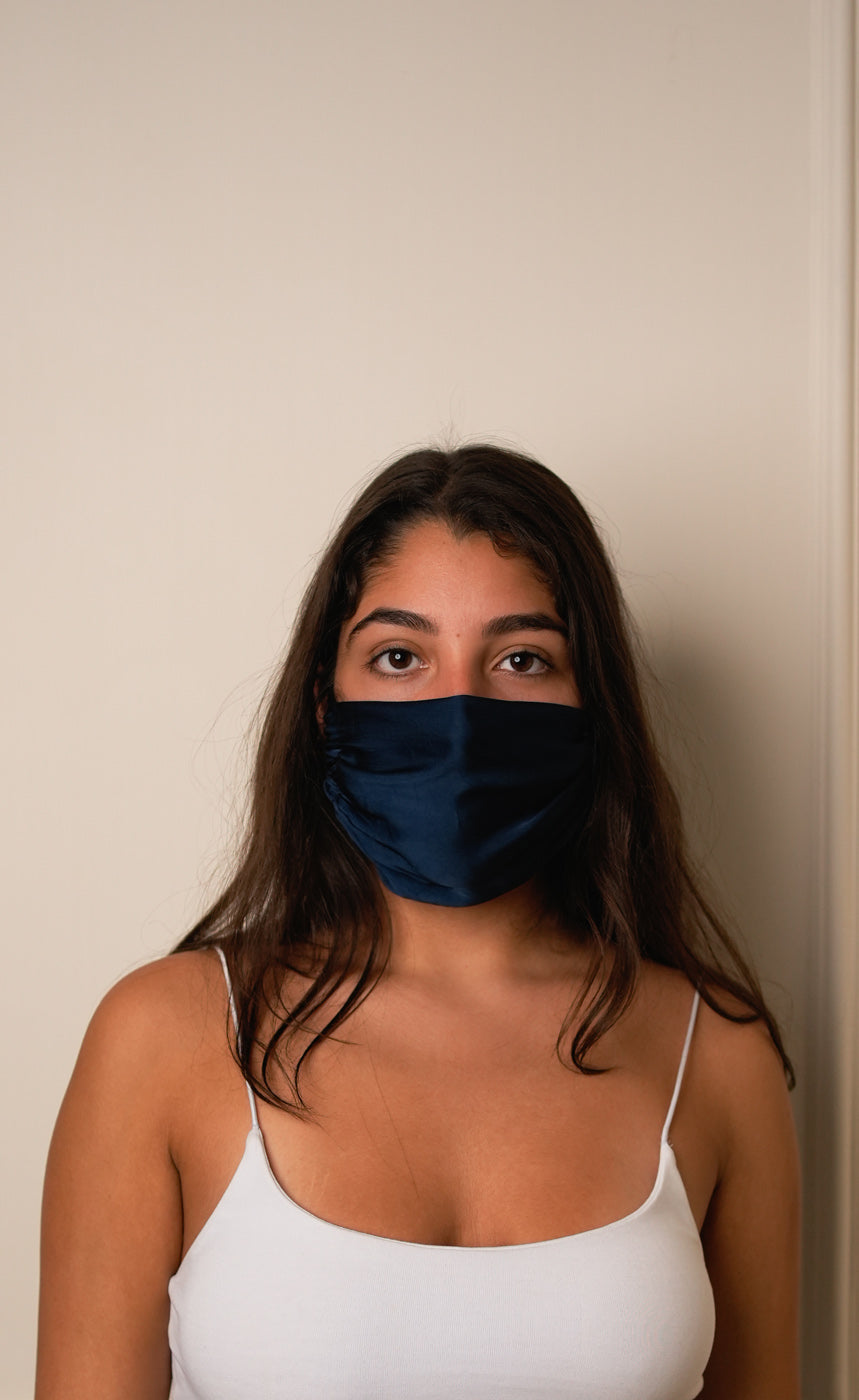 Woman wearing a blue face mask against a plain background