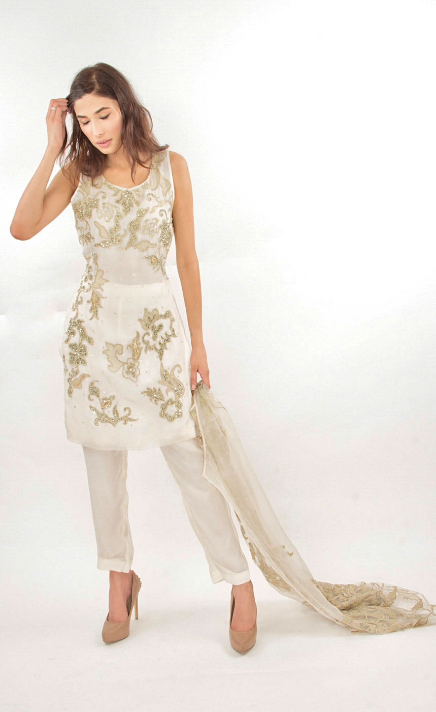 Woman wearing a white outfit with gold embroidery on a white background