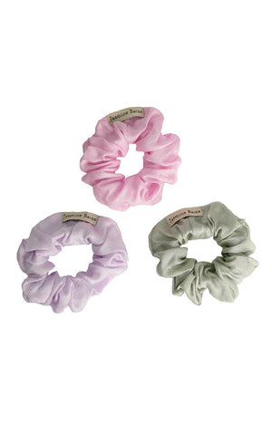 Three satin scrunchies in pink, purple, and green on a white background.