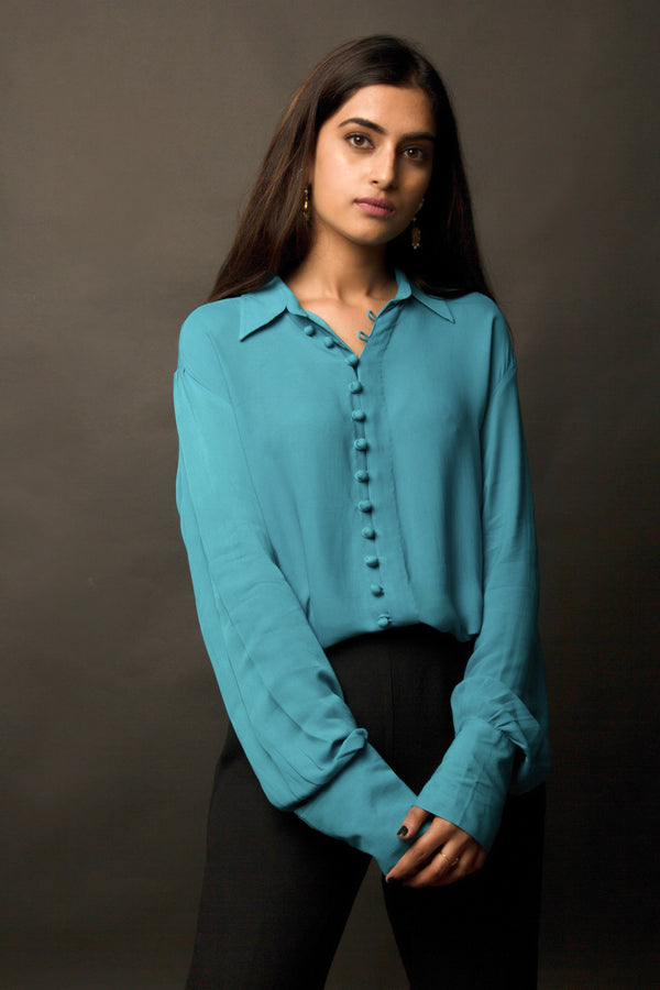 This peacock blue-green classic loop-buttoned business shirt crafted in cupro georgette, with gathered full sleeves, focuses on the modern muse and exudes a sophisticated touch of classic. With its beautiful drop shoulders, it adds a sense of creativity to your shirt style.  