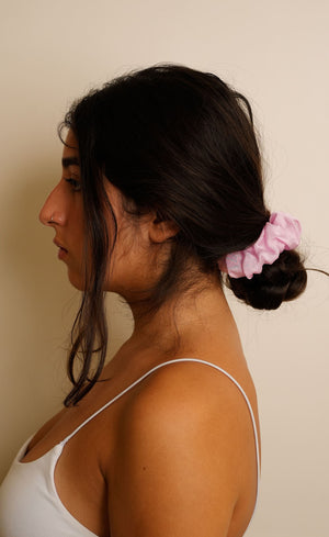 Woman with a pink scrunchie in her hair against a beige background