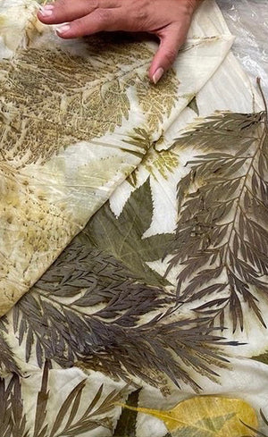 Eco-printed silk fabric with botanical leaf impressions in olive, gold and charcoal tones. 