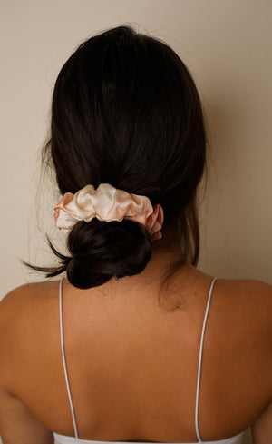 A model wearing a tie and dye scrunchy in a hair bun.