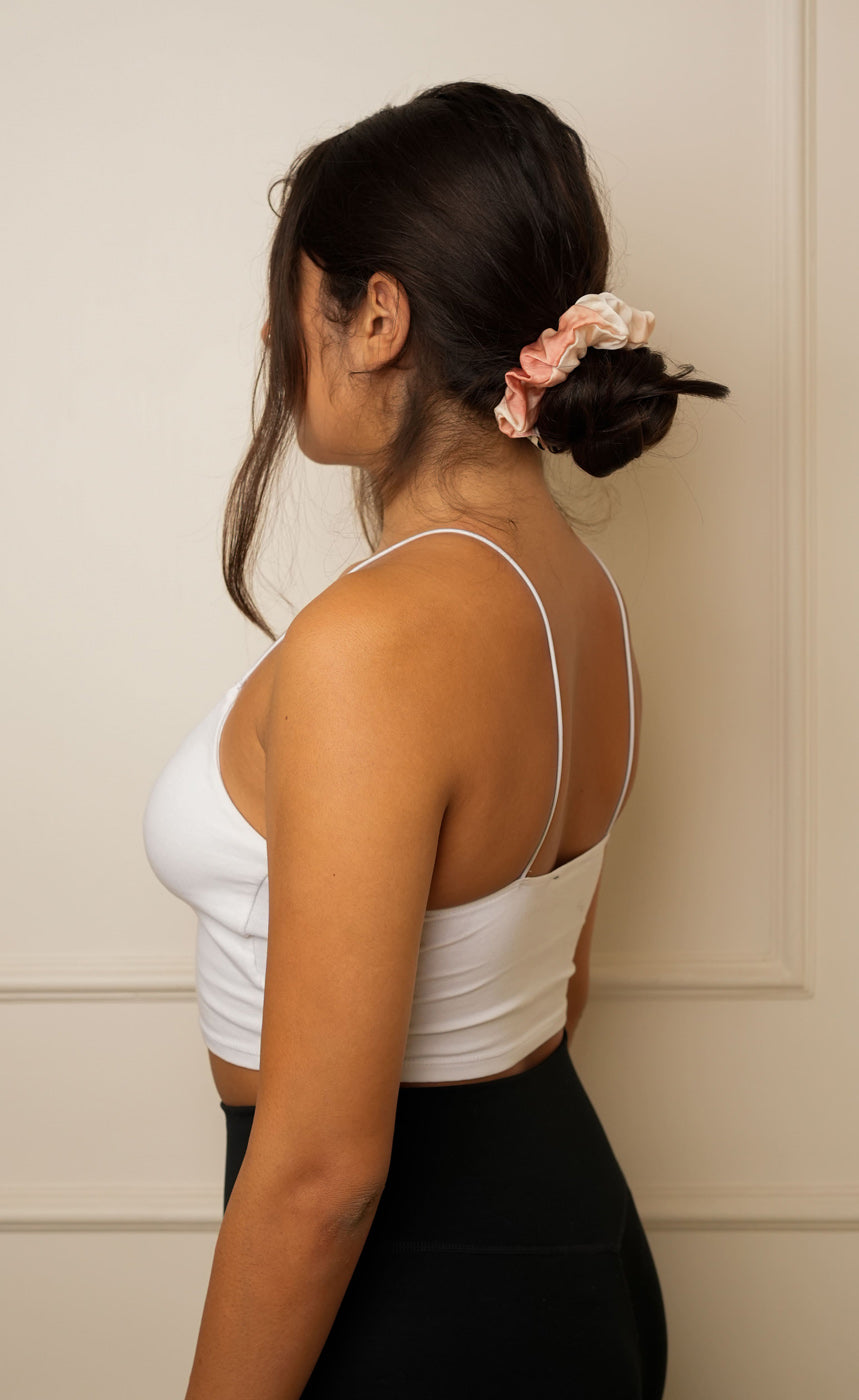 Person with a blue scrunchie in their hair against a beige background