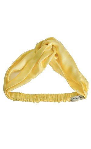 Yellow satin headband with a brand label on a white background