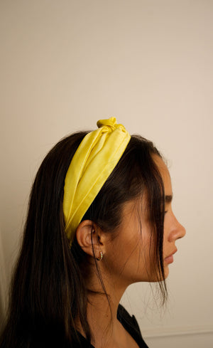 Woman wearing a yellow headband against a plain background