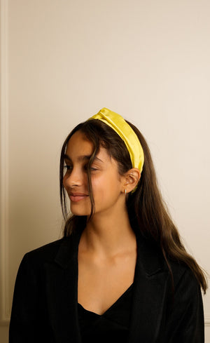 Woman wearing a yellow headband against a plain background
