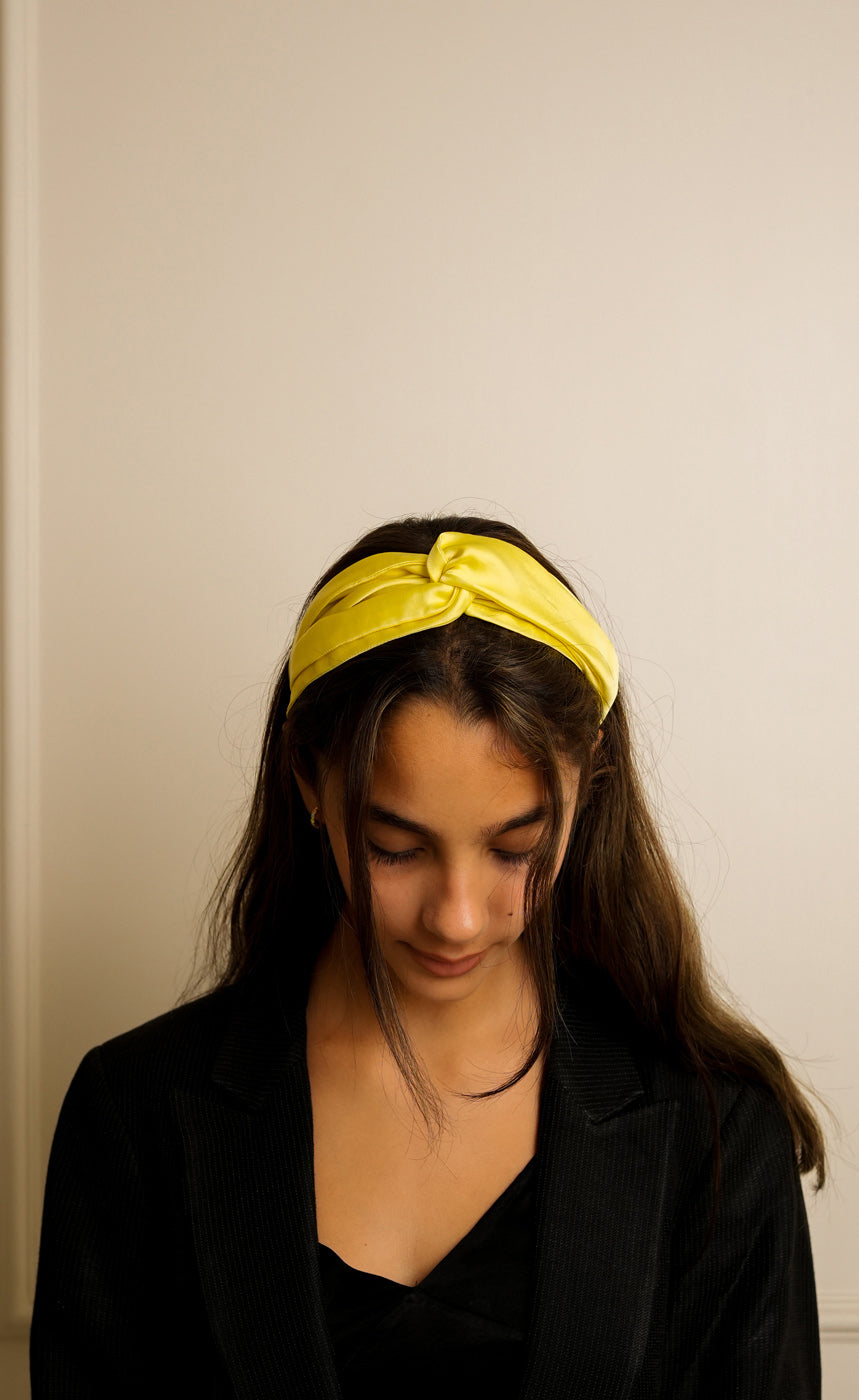 Woman wearing a yellow headband against a plain background