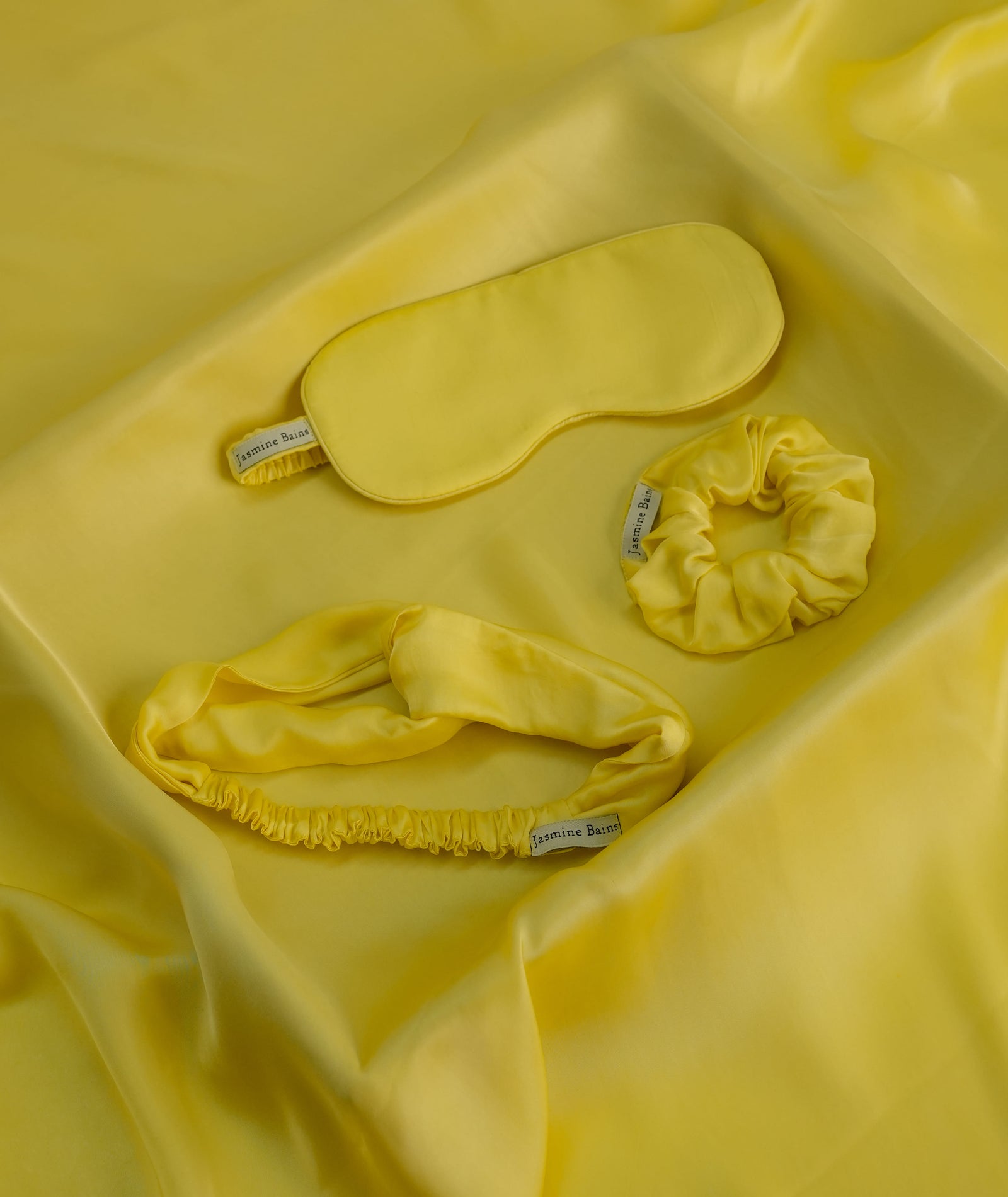 Lemon Yellow Bemberg satin sleep mask, knotted headband and scrunchie flat lay — Jasmine Bains three-piece set