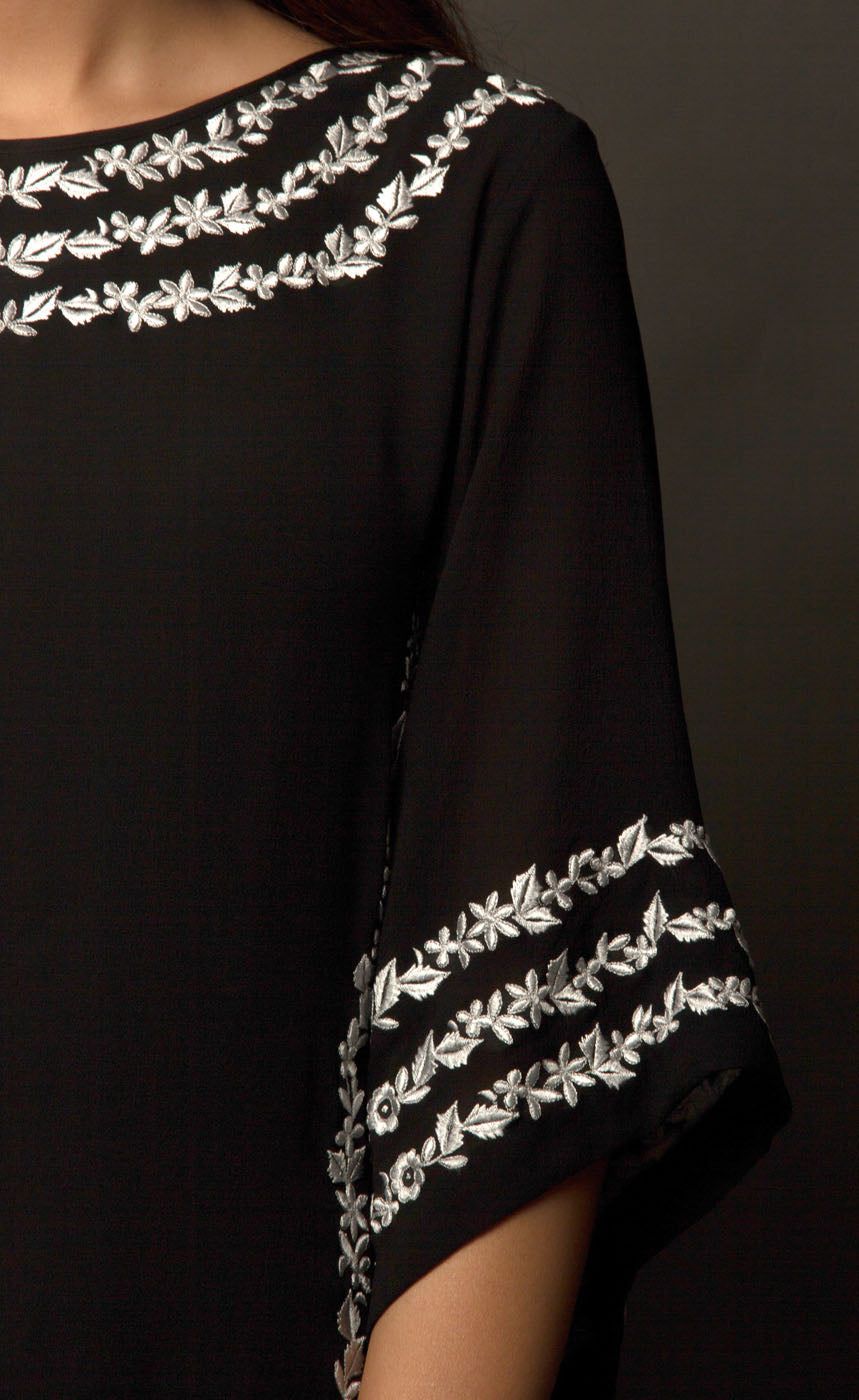 The muse here is wearing an alluring black kaftan. This is a cupro georgette kaftan intricately embroidered with our signature raised thread-work on the neckline, high slits and flared sleeves having a zipper at the back center. The look is completed when paired with cupro georgette slim trousers.