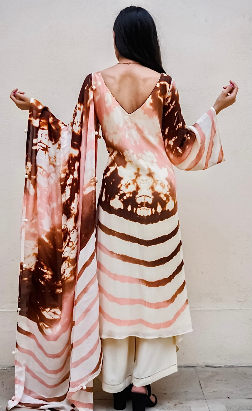 The blend of abstract dye on the top with accents of blush, copper and rust, represents the colourful sunsets of Mykonos balancing with the calming waves at the bottom half. The sleeves and the dupatta carry the same twin dye technique as the Kurta. 