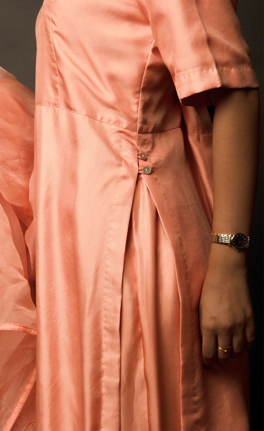 This is a beautiful burnt peach gharara suit set. The muse is wearing a simple yet an elegant kurta with yoke along the waistline paired with gharara having intricate  zari motifs on it. The suit-set is further accompanied by an organza dupatta with appliqué embroidery on it along the width and is finished with a raw silk border.