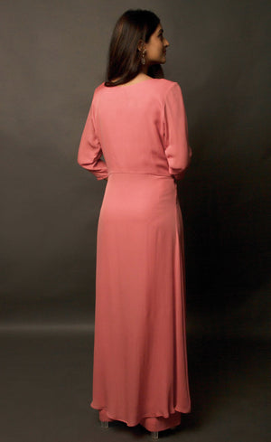 The muse here is wearing a simple and elegant front-slit dress with palazzos in carrot pink. The dress comprises of an upper yoke and a simple v-neckline which is further having a vertical buttoned detail on yoke and a high slit in the middle center. It is further paired with cupro georgette flowy wide legged palazzos.