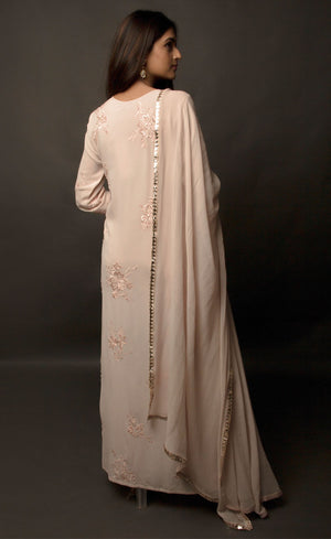 Dusty Rose side slit suit set, crafted in georgette, fully embroidered with signature flat threadwork topped with sequins spray accompanied by a dupatta with rose gold mukaish border. The ensemble carries a strong of a confident style because of the slim straight trousers underneath, the bottom of the trousers is finished by our signature buttoned hemline style. Flaunt your chic style in this elaborately worked ensemble, the muse radiates a modern, yet classic vibe. 