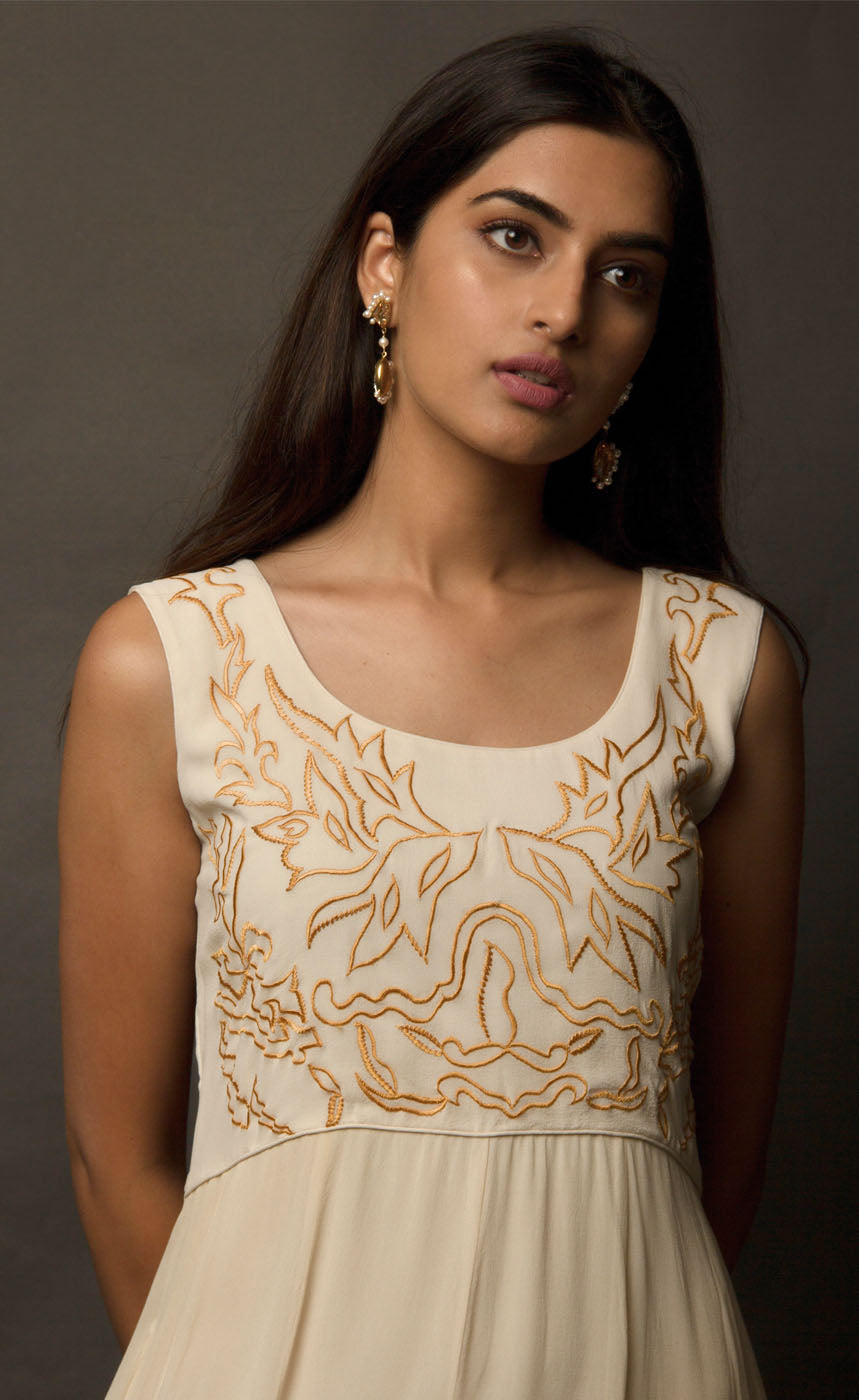 This particular ivory dress in georgette carries a series of thin beautiful long floor length panels from waist down, the yoke is embroidered with a rust colour thread-work, the front and back of the yoke is embroidered with an intentional different pattern, the back yoke embroidery is more prominent and dense than the front. The knee down has been treated with hand tie and dye Batik technique in deep rust and brown accents over the ivory base. 