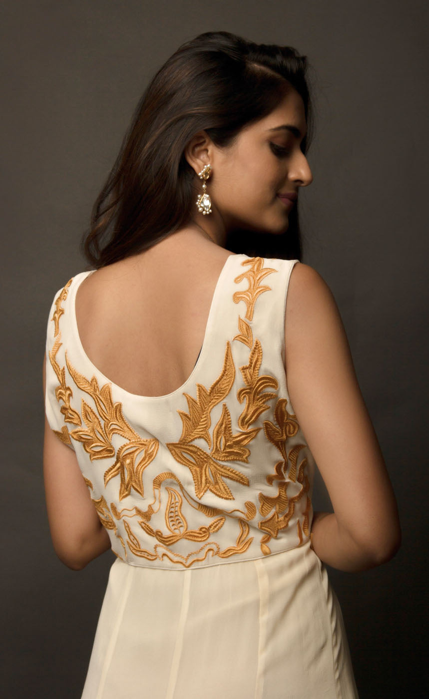 This particular ivory dress in georgette carries a series of thin beautiful long floor length panels from waist down, the yoke is embroidered with a rust colour thread-work, the front and back of the yoke is embroidered with an intentional different pattern, the back yoke embroidery is more prominent and dense than the front. The knee down has been treated with hand tie and dye Batik technique in deep rust and brown accents over the ivory base. 