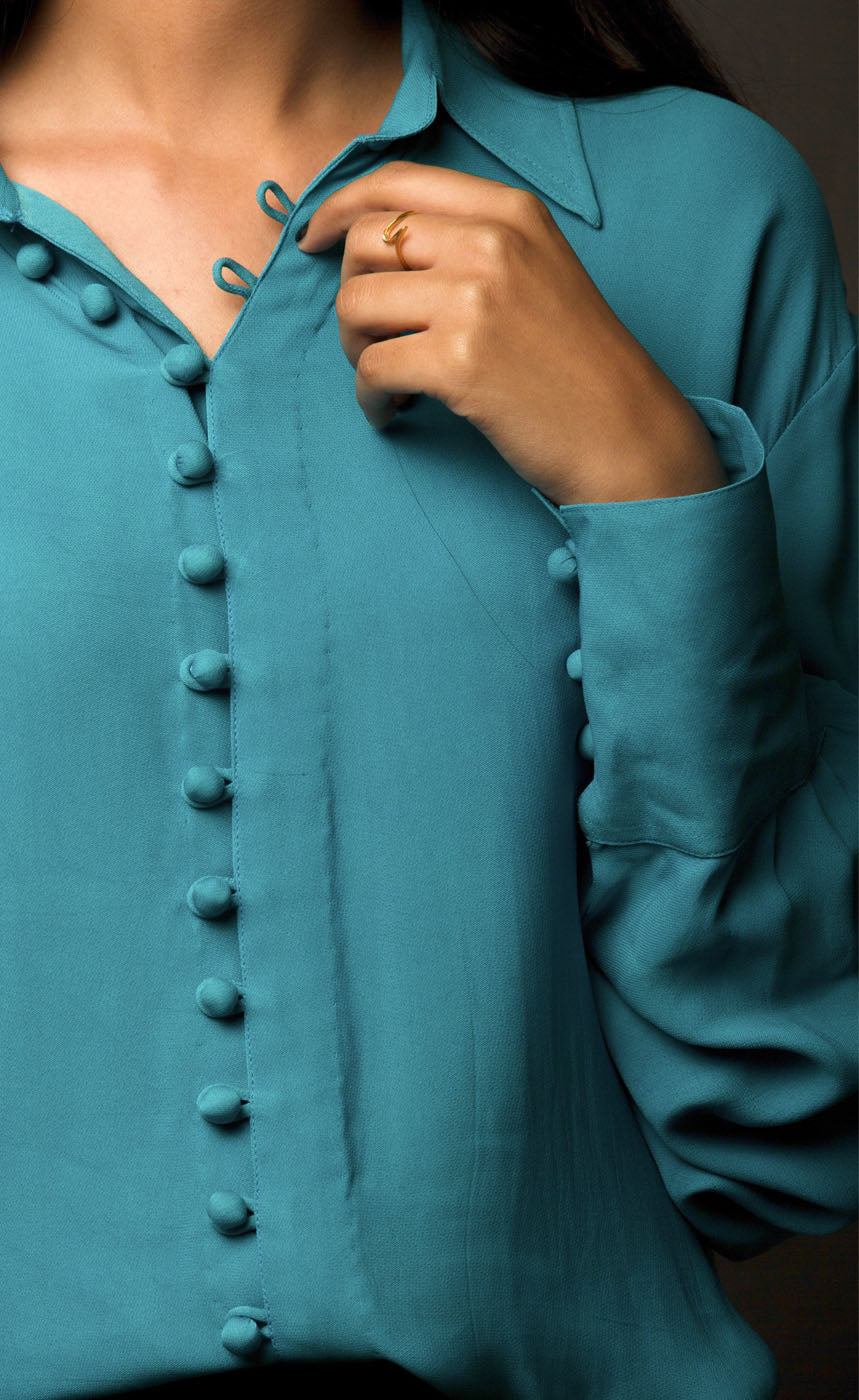 This peacock blue-green classic loop-buttoned business shirt crafted in cupro georgette, with gathered full sleeves, focuses on the modern muse and exudes a sophisticated touch of classic. With its beautiful drop shoulders, it adds a sense of creativity to your shirt style.  