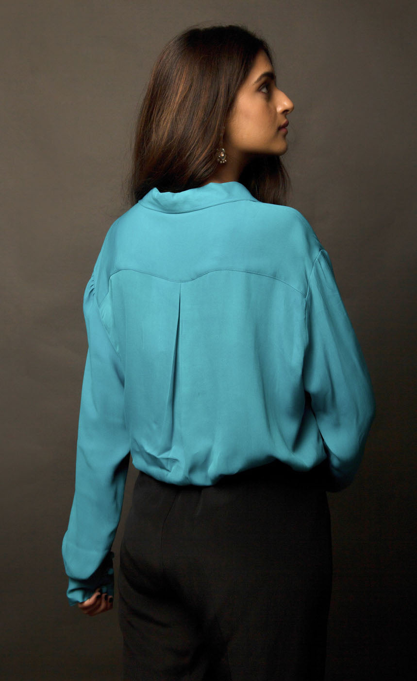 This peacock blue-green classic loop-buttoned business shirt crafted in cupro georgette, with gathered full sleeves, focuses on the modern muse and exudes a sophisticated touch of classic. With its beautiful drop shoulders, it adds a sense of creativity to your shirt style.  