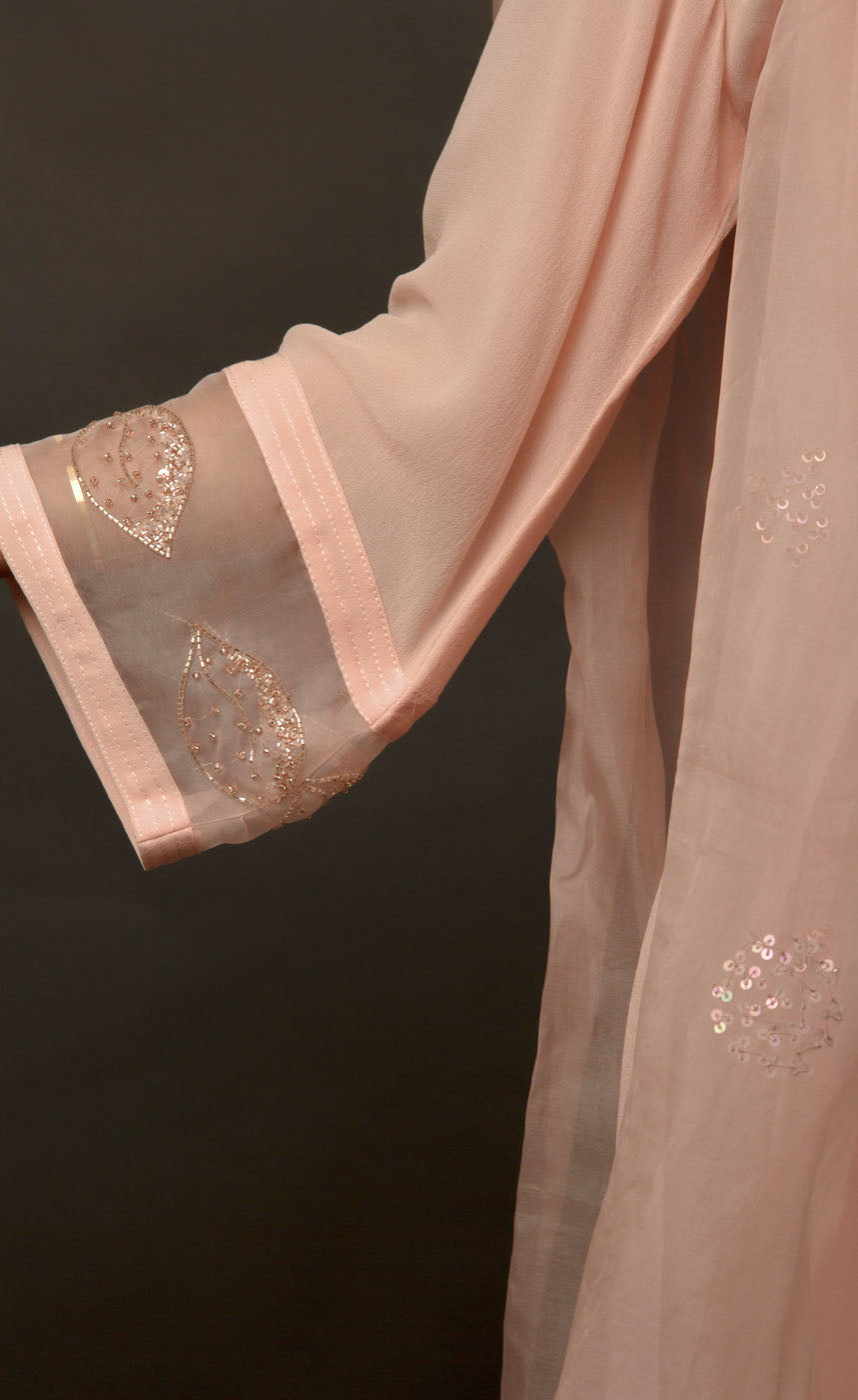 The muse is wearing a loop-buttoned suit set stitched in a lightweight georgette, minimally embellished with tonal glass beads in powder peach and translucent vibe.