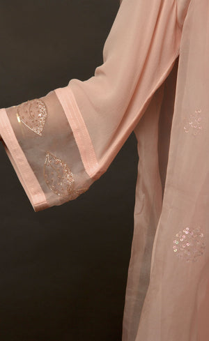 The muse is wearing a loop-buttoned suit set stitched in a lightweight georgette, minimally embellished with tonal glass beads in powder peach and translucent vibe.